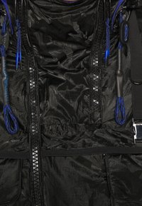 Black jacket with textured fabric, blue and black drawstrings, zippers down front, and a silver Emporio Armani tag on right side.