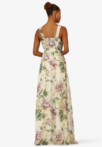 Floral Maxi-Kleid aus leichtem Stoff. Es hat ein geschmücktes Oberteil, breite Träger und ein Muster aus großen lila und gelben Blumen auf einem hellen Hintergrund.