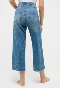 Light blue, wide-leg denim jeans with a high waist and two back pockets. Features a smooth texture and finished hems.