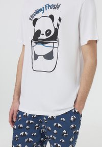 T-shirt bianco in cotone con una grafica di un panda e la scritta "Feeling Fresh!", abbinato a pantaloni da pigiama blu navy con un motivo a panda ripetuto.