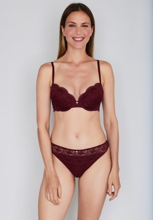 Burgundy lace lingerie set featuring a padded bra with scalloped edges and matching thong with intricate detailing along the waistband.