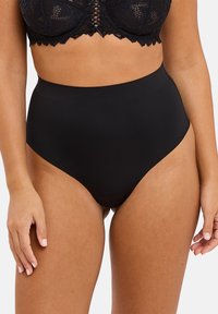 Culotte taille haute noire fabriquée en matériau lisse et extensible. Présente un design sans coutures avec aucune couture visible et une coupe mi-haute.