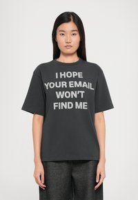 Grå bomulds-t-shirt med korte ærmer og rund hals. Har fed hvid tekst: "JEG HÅBER, AT DIN EMAIL IKKE FINDER MIG" på fronten.