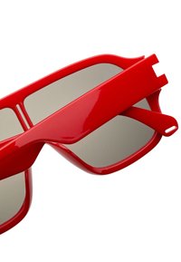 Lunettes de soleil rouges avec une finition brillante, un design angulaire et des verres gris. Présentent des branches épaisses et distinctives pour un look audacieux.