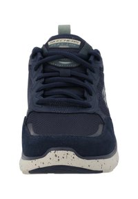 Scarpa sportiva blu navy con parte superiore in rete e dettagli in suede, punta arrotondata e suola bianca maculata. Include lacci e linguetta sul tallone.