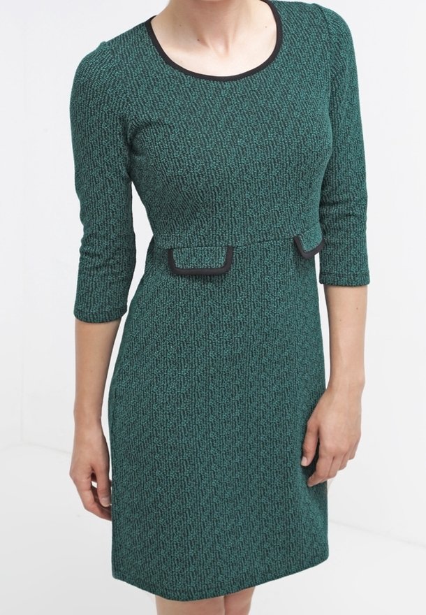 Vihreä teksturoitu mekko, jossa on kolme neljänneshihaa, pyöreä kaula-aukko ja mustat yksityiskohdat vyötäröllä. Slim fit ja polvipituinen muotoilu.