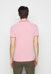 Korte mouwen polo shirt in lichtroze stof met een gestructureerde afwerking, voorzien van een klassieke kraag en contrasterende gestreepte accenten op de mouwen.