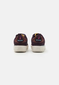 Nike tenisice s ljubičastom mrežastom gornjom površinom, žutim naglascima i strukturalnom bijelom potplatu s kontrastnim brendiranjem na peti.