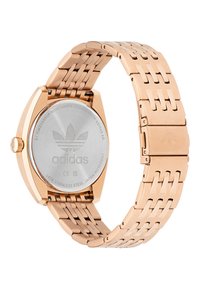 Montre en acier inoxydable doré avec un bracelet à maillons, dotée d'un boîtier rond et d'un logo gravé au dos. Résistante à l'eau jusqu'à 5 ATM.