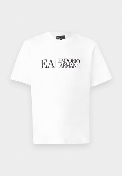Witte T-shirt met korte mouwen en zwarte "EA Emporio Armani" tekstlogo gecentreerd op de voorkant tegen een effen achtergrond.