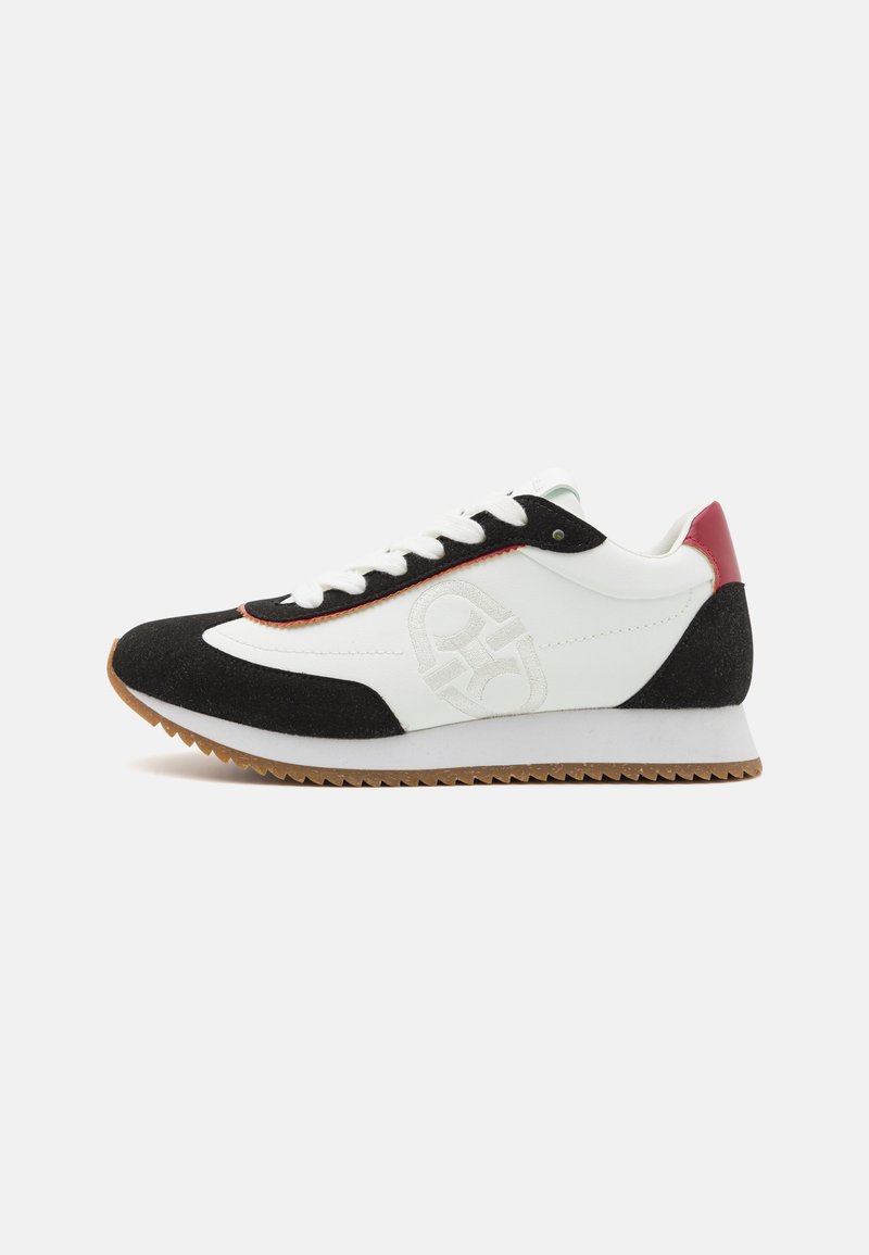 Hvit og svart sneakers med overdel i semsket skinn, gummisåle og røde detaljer med logo på siden. Klassisk snøring design.