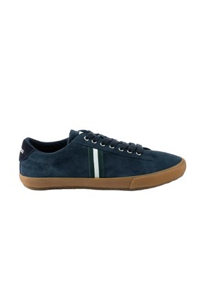 Zapatilla de ante azul marino con suela de goma marrón, rayas laterales en negro y blanco, y cordones negros, vista desde el lado exterior.