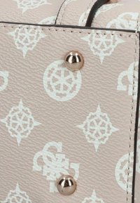 Lichtroze textiel met structuur, voorzien van witte patronen en een decoratieve gouden stud. Opvallende ontwerpen zijn onder andere geometrische vormen en logo's.