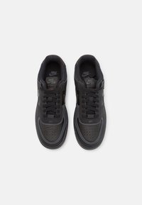 Mustat Nike Air Force 1 -kengät, joissa on tekstuuripäähineet ja Nike-logot nähtävissä kielellä ja pohjallisilla, nähtynä ylhäältä.