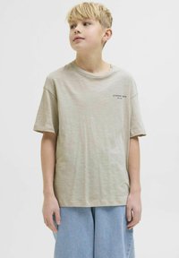 Lichtbeige t-shirt met een ronde halslijn en korte mouwen, voorzien van subtiele textuur en een klein bedrukt logo aan de voorkant.
