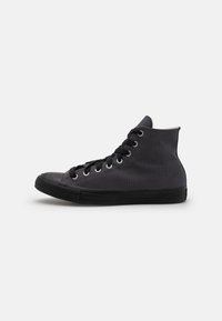 Tenis high-top realizat din pânză neagră cu o suprafață texturată, având vârful din cauciuc negru, gromete și șireturi negre. Design simplu.