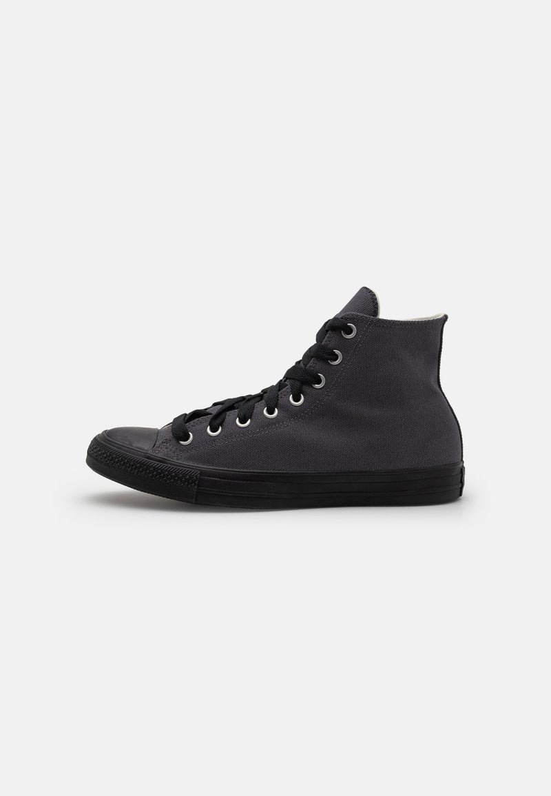 Tenis high-top realizat din pânză neagră cu o suprafață texturată, având vârful din cauciuc negru, gromete și șireturi negre. Design simplu.