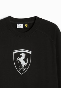 Sort sweatshirt med rund hals, ribbede ærmer og et fremtrædende hvidt springende heste-logo inden for et skjold. Brandlabel inkluderet.