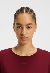 Burgundy t-shirt med rund halsringning, tillverkad av mjukt tyg. Har en subtil "BOSS"-logotyp på framsidan, slät yta och korta ärmar.