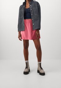 Kurtka dżinsowa w pionowe paski, krótki ciemny top na ramiączkach, różowa mini spódniczka oraz jasnobeżowe sznurowane botki na grubej podeszwie.