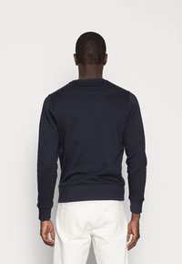 Marineblauwe sweatshirt van zacht katoen, met lange mouwen, geribbelde boorden en een ronde hals. Eenvoudig ontwerp zonder zichtbare patronen of logo's.