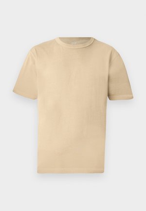 T-shirt beige en coton à manches courtes et col rond avec une coupe décontractée et des détails de couture subtils sur un fond clair.