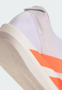 Svetlofialová športová obuv s textúrovaným sieťovaným zvrškom, oranžovými akcentmi a bielou tlmenou podrážkou. Má elegantný, moderný dizajn.