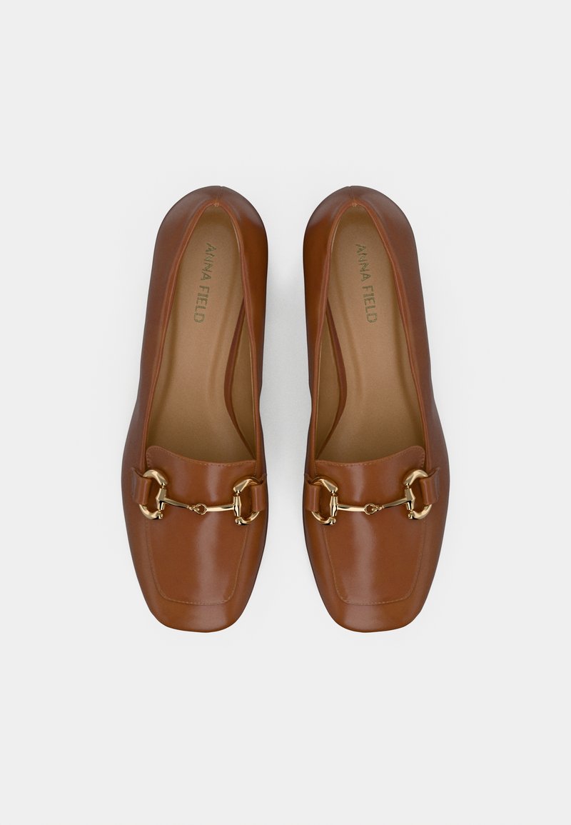 Mocassins en cuir marron avec un bout carré, ornés d'une chaîne dorée et d'une texture lisse, marqués "ANNA FIELD" sur la semelle intérieure.