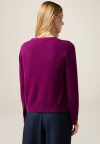 Maglione fucsia a maglia con maniche lunghe e scollo rotondo, caratterizzato da orlo e polsini a coste. Tessuto morbido con dettagli minimali.