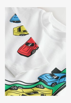 T-shirt en coton blanc avec des graphiques de voitures colorés en rouge, bleu, jaune et vert. Coupe classique avec col rond et manches courtes.