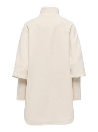 Manteau long couleur crème avec col montant et poignets en maille côtelée superposés s'étendant des manches, vu de dos.