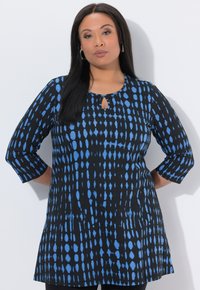 Sort tunika med blåt mønster, med halsudskæring i nøglehul og trekvartlange ærmer. Blødt stof, løs pasform og tekstureret design.