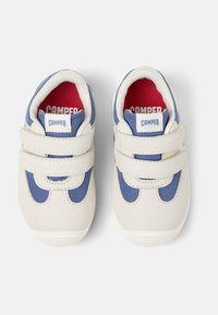 Sneaker bianchi e blu con strap in velcro e interno rosso, caratterizzati da una forma arrotondata e dettagli in tessuto testurizzato.