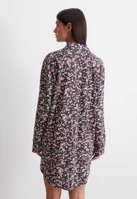 Abito chemisier a maniche lunghe di color maroon scuro con un motivo floreale in rosa e bianco. Tessuto morbido, colletto e orlo leggermente curvato.