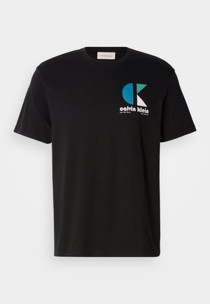 Camiseta de algodón negra con un diseño gráfico que presenta el logotipo "calvin klein" en blanco, verde azulado y rosa. Cuello redondo y mangas cortas.