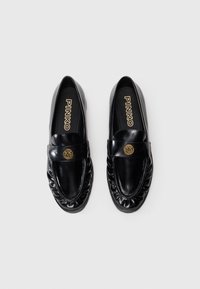 Mustad mustad nahast loafers, sujuva viimistlusega, dekoratiivse kuldkuuliga, kogutud detailidega äärtes ja lame tallaga.