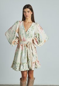 Blumenkleid aus leichtem Stoff. Verfügt über lange, gepuffte Ärmel, einen tiefen V-Ausschnitt, eine taillierte Taille, einen rüschierten Saum und ein mehrfarbiges Blumenmuster.