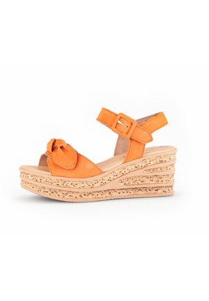 Orange wedge sandals with a knotted bow detail, adjustable ankle strap, and textured cork sole featuring layered grooves.