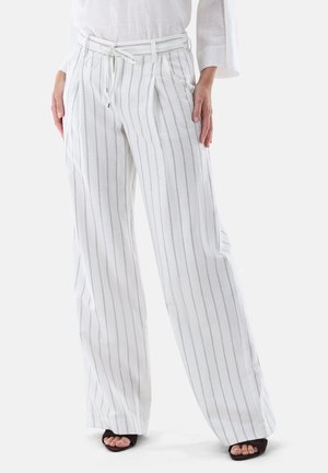 Weiße Hosen mit weitem Bein und dünnen vertikalen schwarzen Streifen, Tunnelzug in der Taille, seitliche Taschen, getragen mit schwarzen offenen Peep-Toe-Absätzen und einem weißen Langarmoberteil.