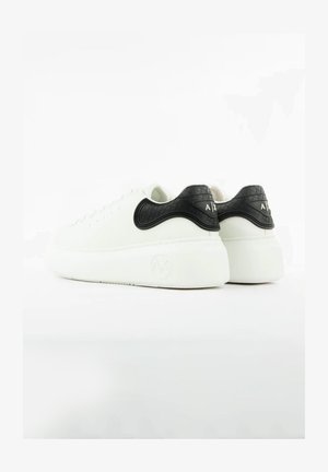 Białe skórzane sneakersy z czarnym, teksturowanym akcentem na pięcie, okrągłym noskiem oraz gumową podeszwą o gładkim wykończeniu z detalem logo.