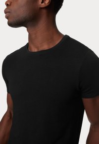 T-shirt nera a maniche corte realizzata in morbido cotone, con un design classico a girocollo e una texture liscia e uniforme.