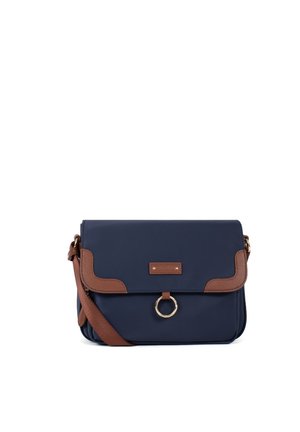Sac bandoulière bleu marine avec garniture en cuir marron, bandoulière ajustable et fermoir circulaire doré sur le rabat avant.