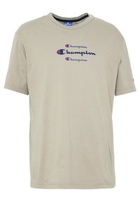 Beige bavlněné tričko s kulatým výstřihem. Na hrudi se nachází logo "Champion" v modrém a červeném písmu. Krátké rukávy, standardní střih.