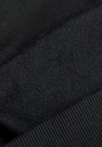 Czarna odzież z gładkiej dzianiny u góry oraz miękkiego, teksturowanego polaru poniżej, z prążkowanym, dzianinowym wykończeniem dolnym.