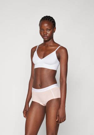 Lichtblauwe bralette met dunne bandjes, gecombineerd met huidkleurige hipster slipjes met een witte taillestrip waarop het 'PIECES' logo in lichtroze is afgebeeld.