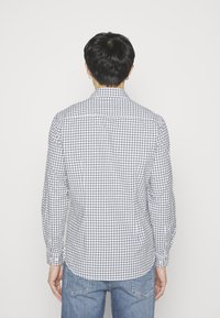 Geruit overhemd met lange mouwen in blauw en wit, voorzien van een button-down kraag, een afgeronde zoom en een getailleerde pasvorm. Draagt het met lichtblauwe spijkerbroek.