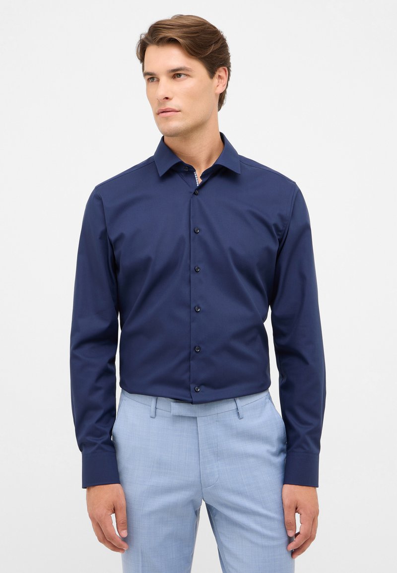 Kobaltblauwe langemouwshirt met een knoopsluiting en een klassieke kraag. Gemaakt van gladde stof met een subtiele glans. Getailleerde pasvorm.