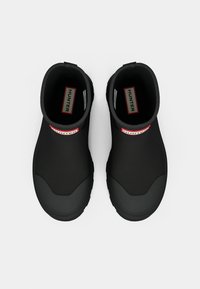 Bottes de cheville noires imperméables en caoutchouc, dotées d'une semelle texturée, d'un bout rond et d'un logo "HUNTER" rouge à l'avant.