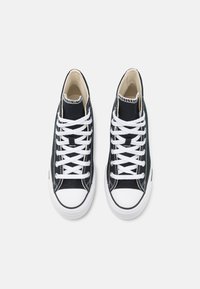 Höga svarta kanvas sneakers med vita snören, gummitåhättor och vita sulor. Har dubbel söm och en texturerad ovansida.