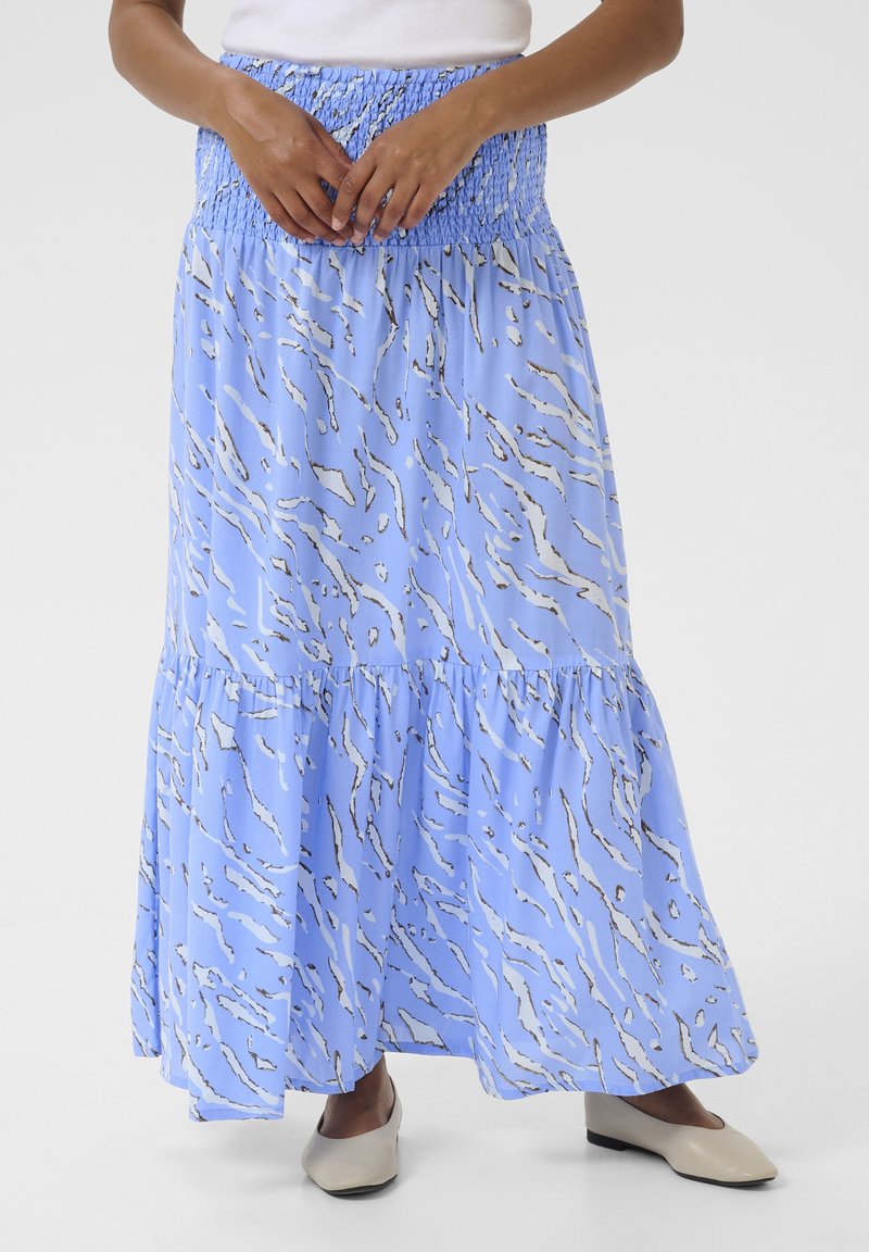 Jupe maxi bleue avec une taille smockée, ornée d'un motif abstrait blanc. Le tissu est léger et fluide avec un design en couches.